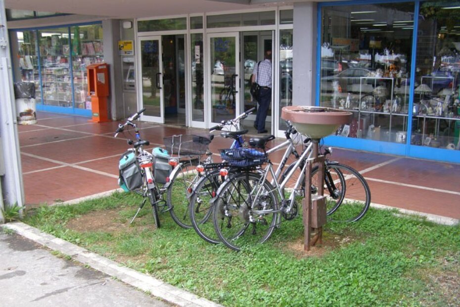 Bicikli parkirani na travi ispred porečke Robne kuće